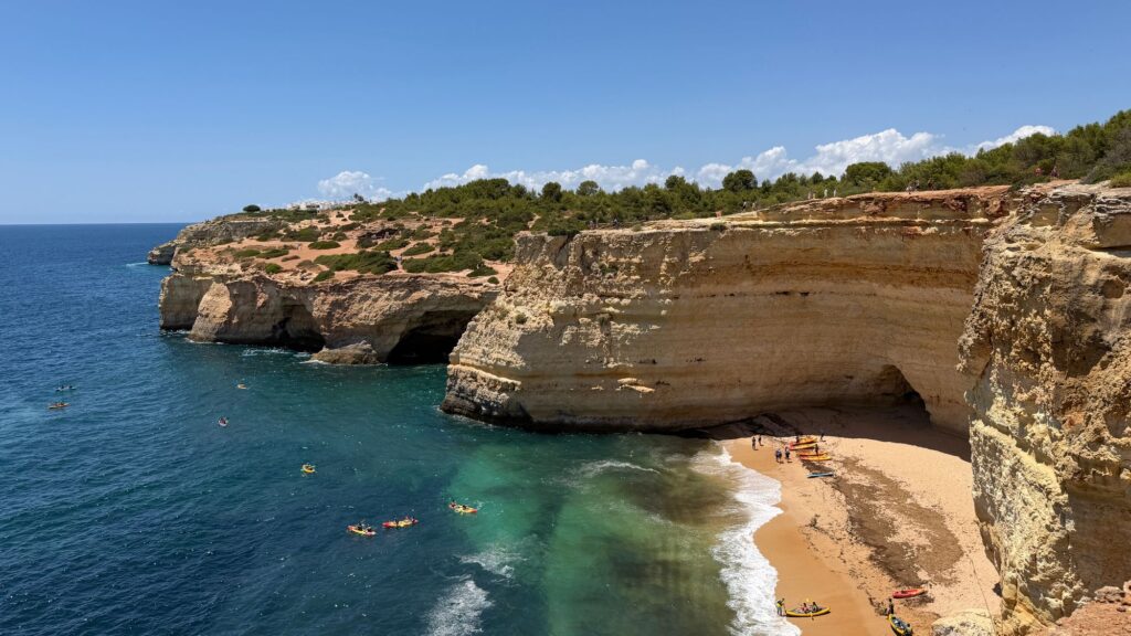 Sea kayakers below golden limestone cliffs on the Algarve coast in Portugal