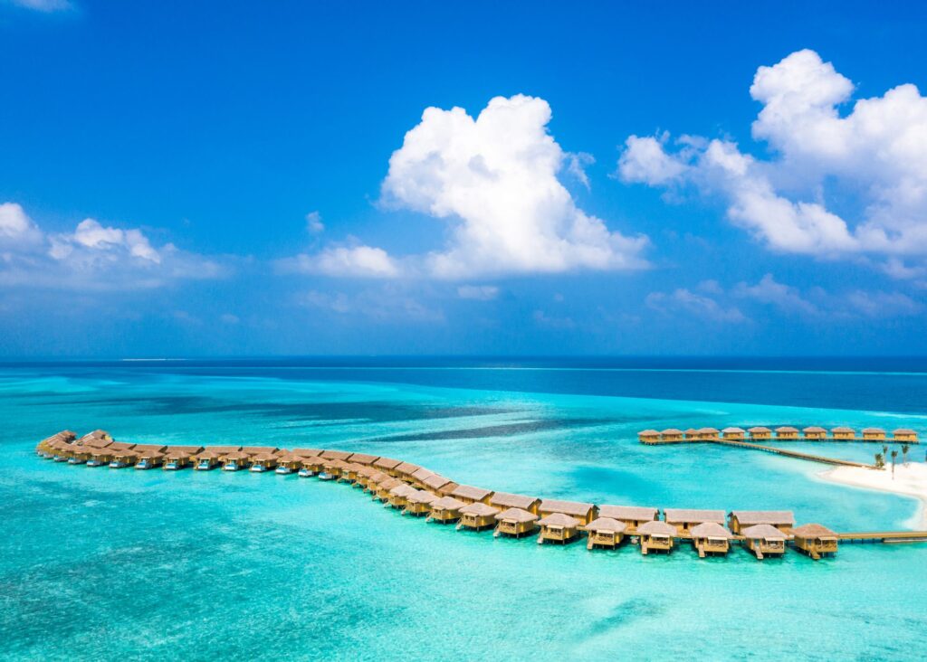 Aerial view of overwater bungalows surrounded by turquoise lagoon water in the Maldives