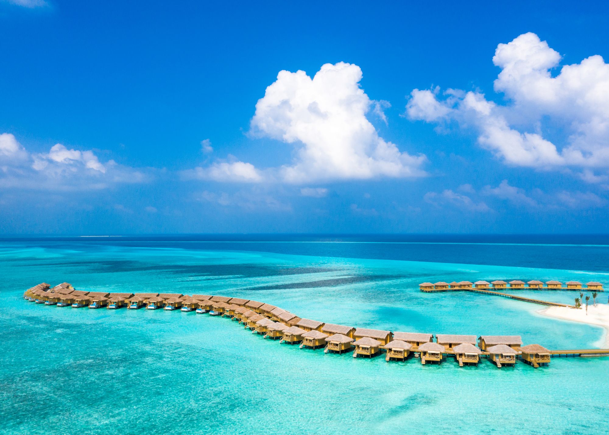 Aerial view of overwater bungalows surrounded by turquoise lagoon water in the Maldives