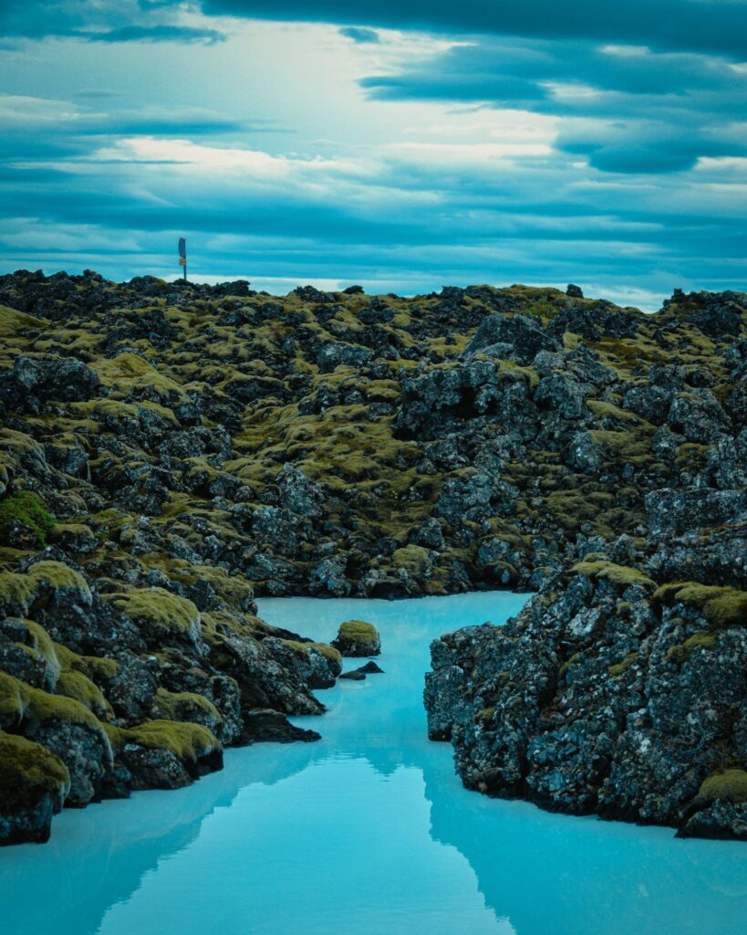 Milky blue geothermal lagoon surrounded by dark lava rock in Iceland at twilight