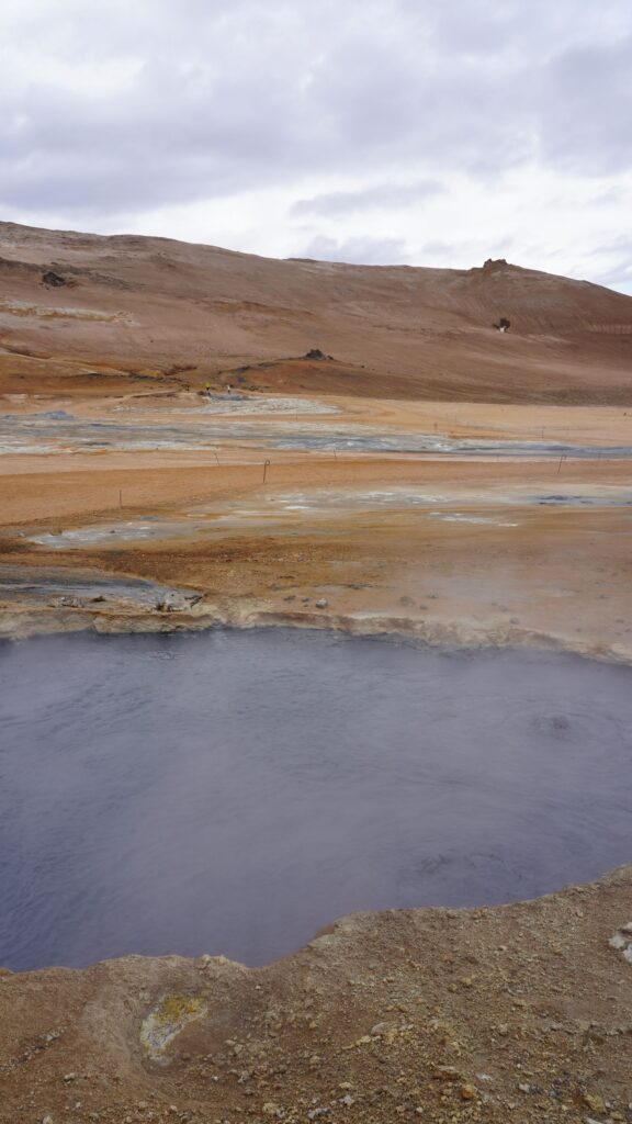 Steaming geothermal pool in a rugged Icelandic landscape