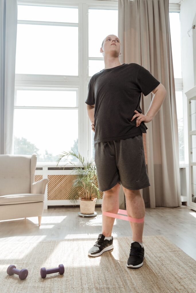 Man exercising at home with a resistance band and dumbbells
